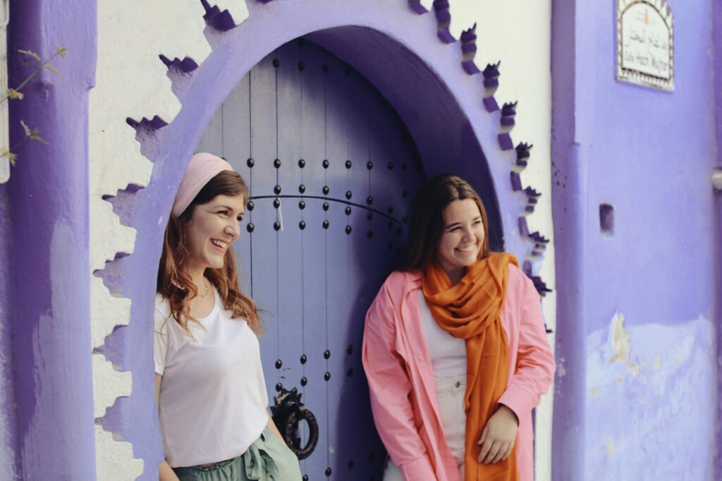 Deux voyageuses souriantes s’amusant devant une magnifique porte au Maroc