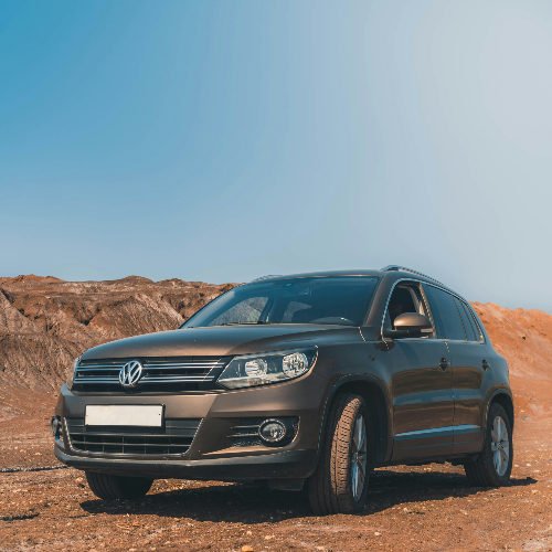 SUV Volkswagen marron garé sur un terrain rocailleux sous un ciel bleu au Maroc, avec un air d’aventure.
