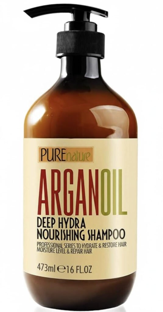Brown bottle with black pump labeled ‘PUREnature ARGAN OIL Deep Hydra Nourishing Shampoo,’ 473ml. Cream label with green and red text.