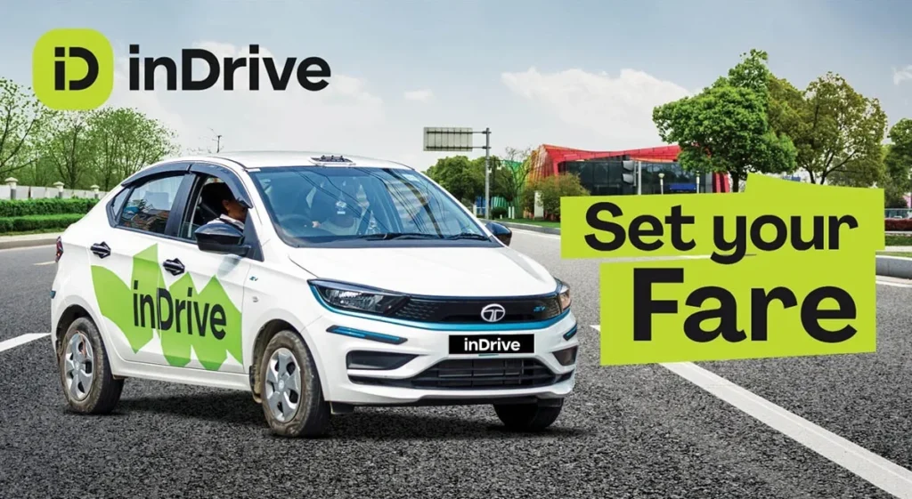 White car with ‘inDrive’ logo driving on road, green trees in background. Text: ‘Set your Fare.’ Bright, sunny setting.
