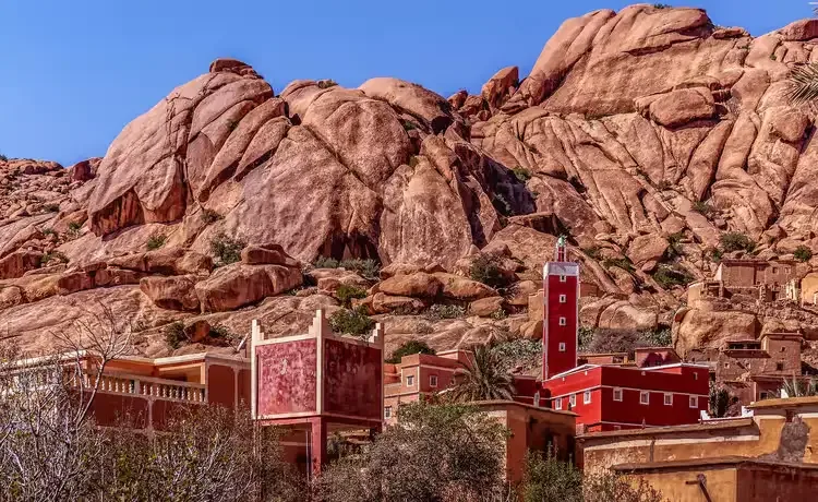 colorful red mosque and the small town of tafraoute next to red giant rocks and a canyon in Morocco