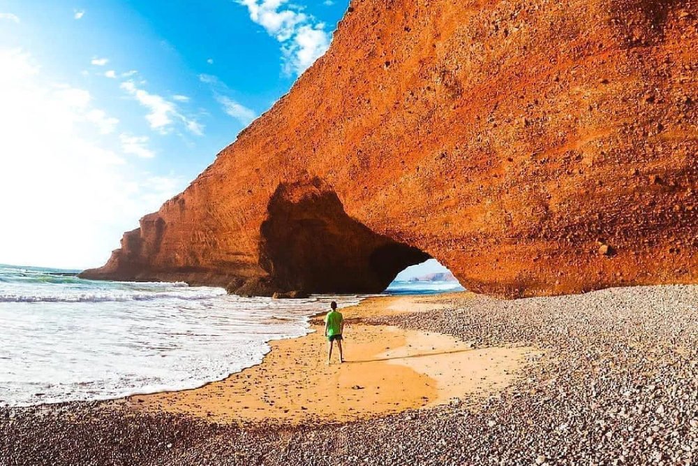a boy standing near the famous arch in legzira beach near sidi ifni morocco