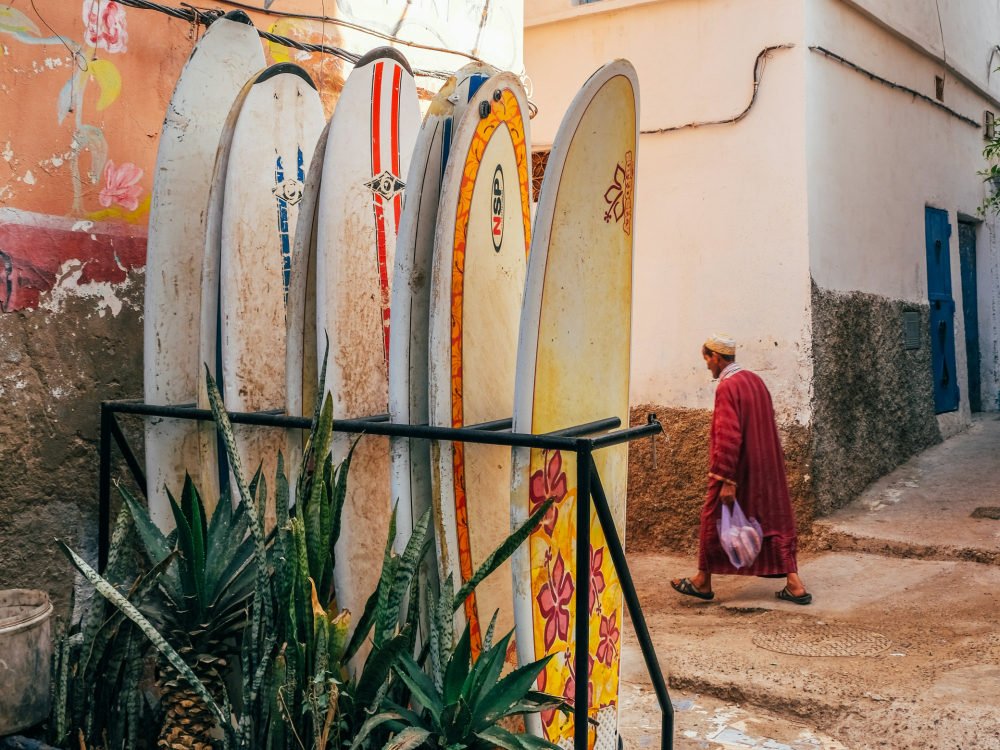 surfboards lined up in taghazout and a local man walking by